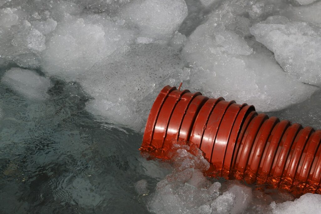 a red pipe sticking out of some ice