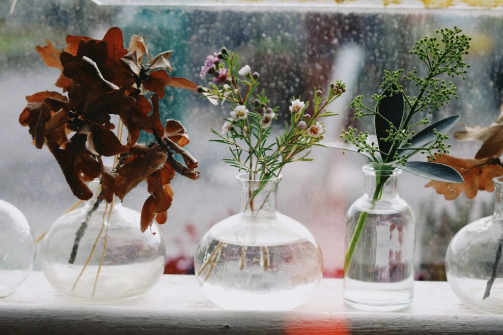 Vases of flowers sit on a windowsill.