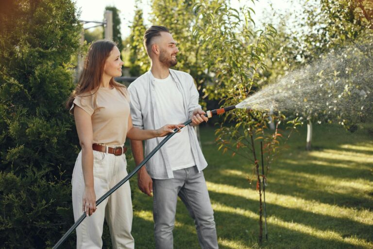 A cheerful couple watering plants in their sunny garden, enjoying outdoor gardening activities.