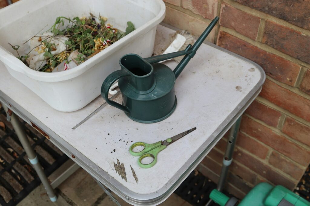 Gardening tools and a bin sit on a table.
