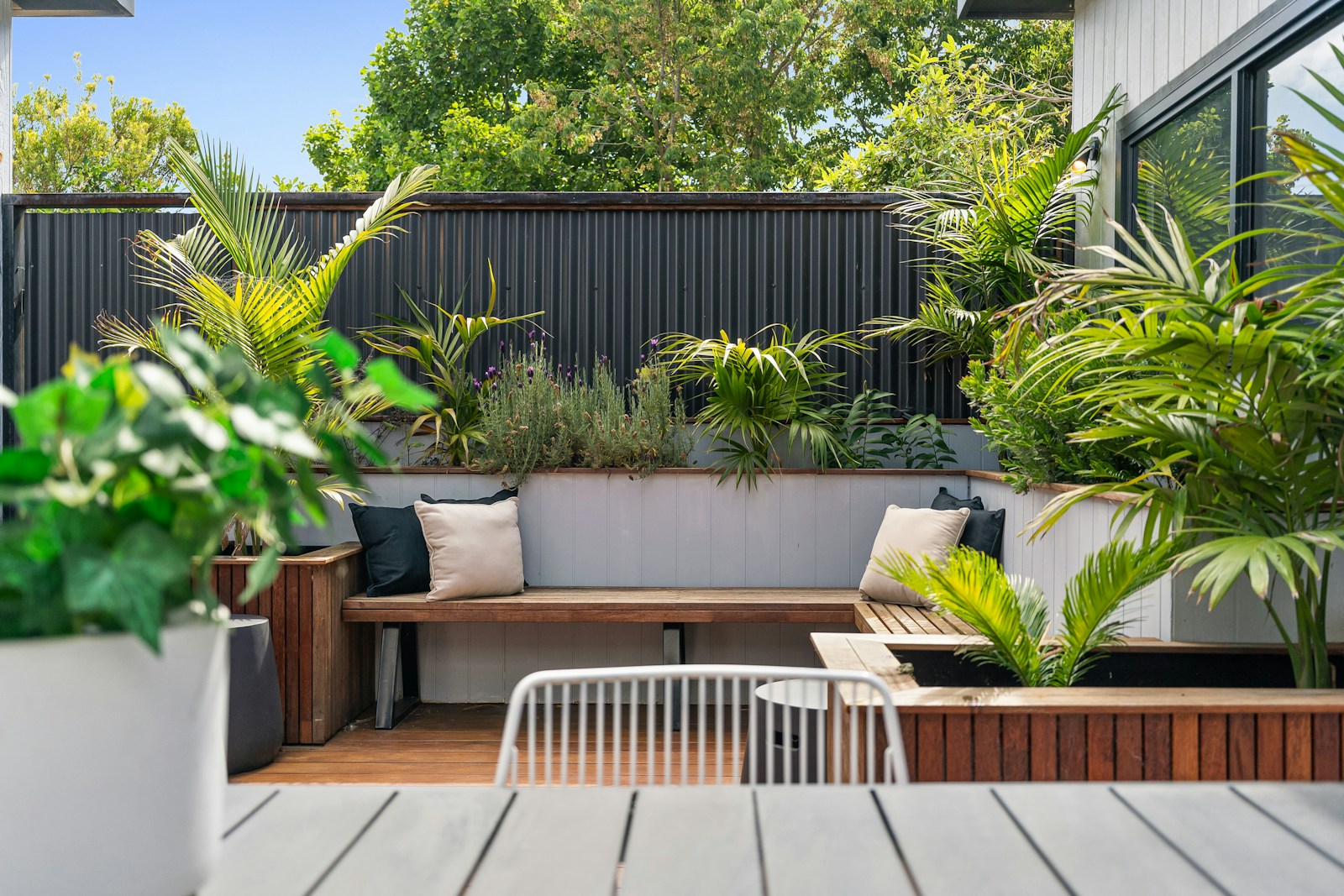 A patio with a wooden table and white chairs