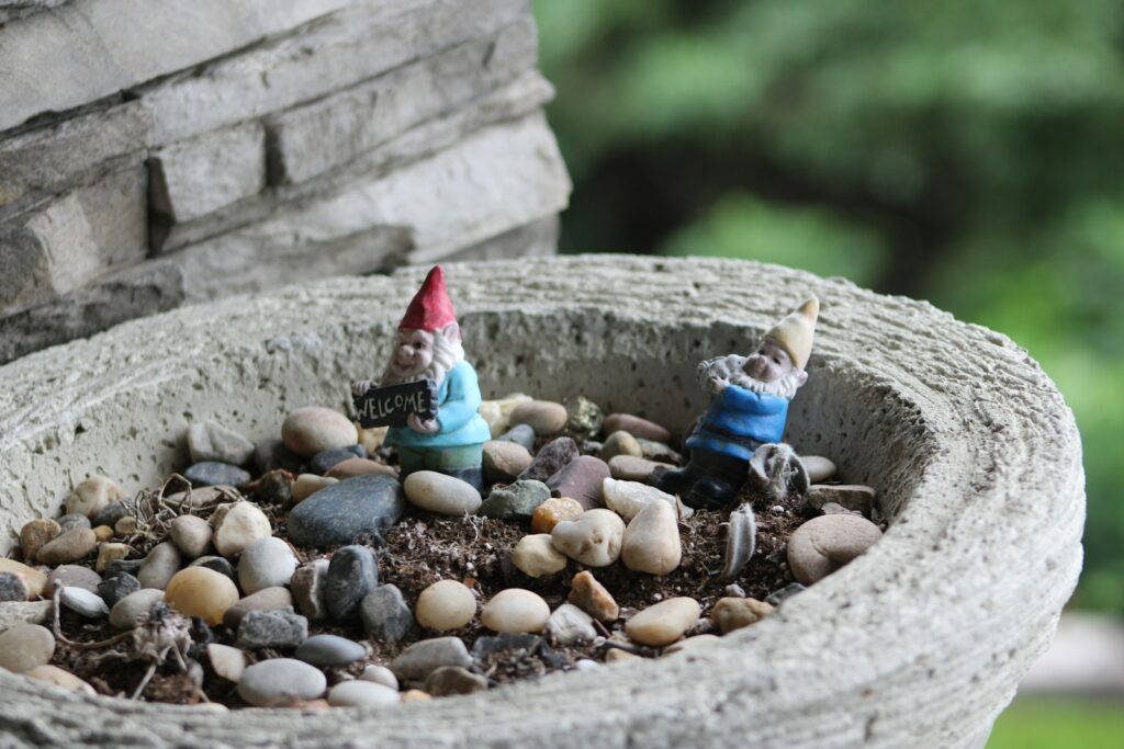 Gnomes are in a pot with pebbles and soil.