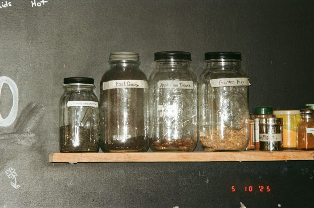 Glass jars with contents are on a shelf.