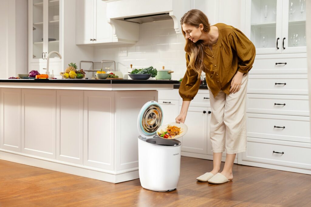 A woman standing next to a trash can in a kitchen