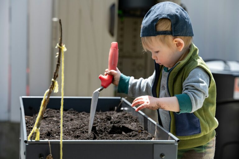 a young boy using a red tool to stir a substance in a container