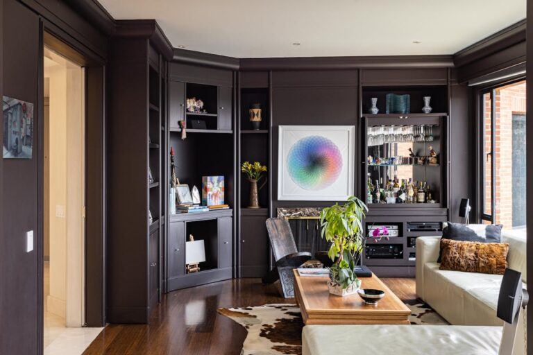 Elegant living room with dark cabinets, lush plants, and cozy seating.