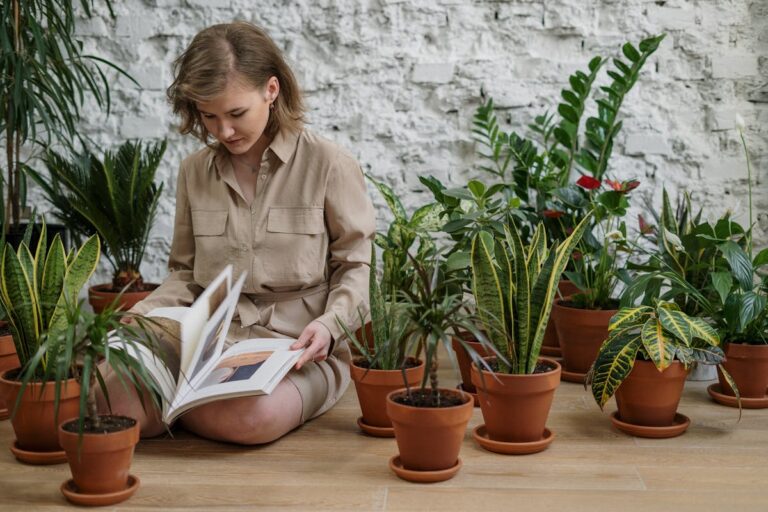 Woman reading a book surrounded by various indoor potted plants, creating a calming atmosphere.
