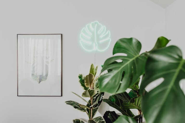 Stylish home decor featuring a neon monstera sign and lush houseplants.