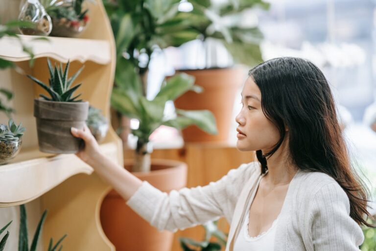 Asian woman browsing potted plants in a tranquil indoor store setting.