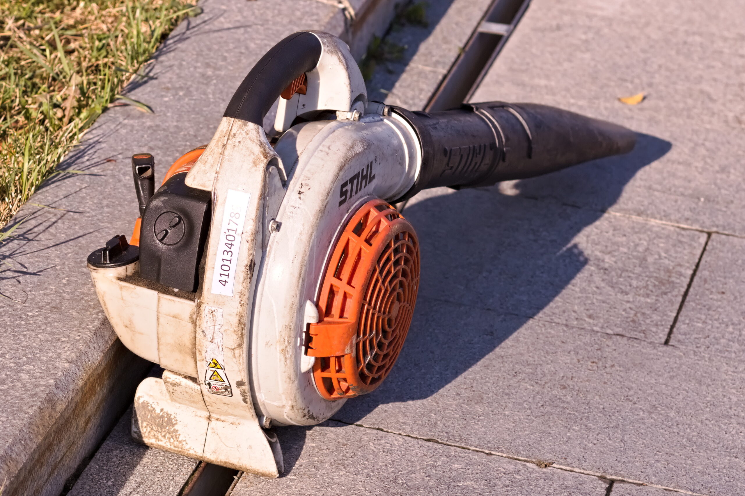 A handheld gas-powered leaf blower used to clear fallen autumn leaves